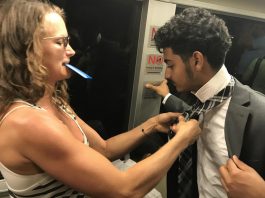 Fellow Passenger Helps Young Man With His Tie On Train