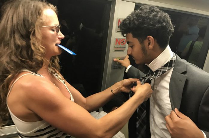 Fellow Passenger Helps Young Man With His Tie On Train